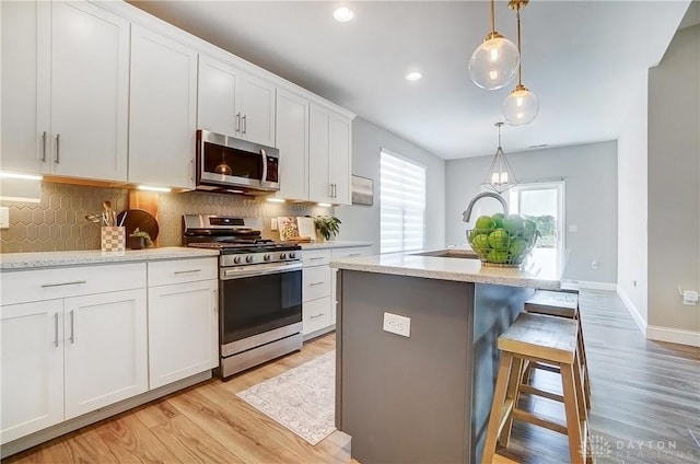 1002 Belfast Dr, Sugarcreek Township, OH 45440 - kitchen with a sink, stainless steel appliances, white cabinetry, a kitchen breakfast bar, and backsplash