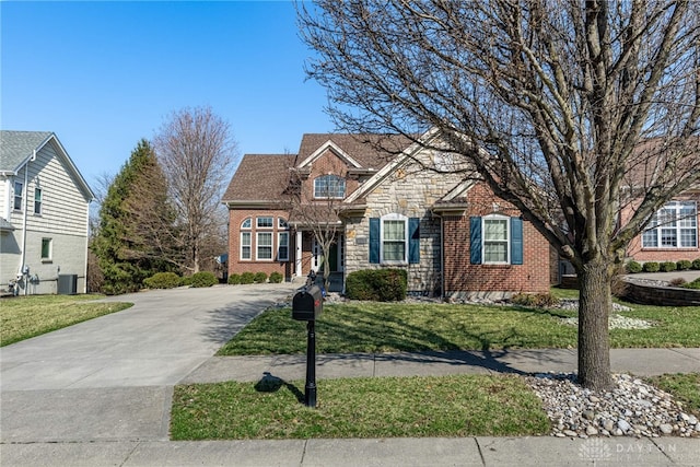 view of front of home with stone siding, brick siding, concrete driveway, and a front yard