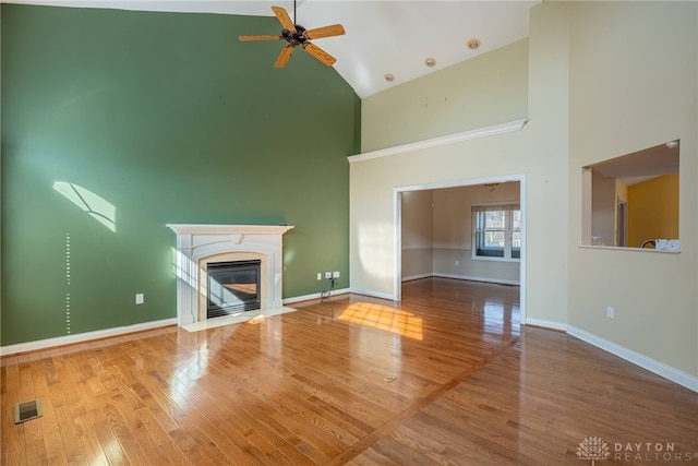 unfurnished living room with wood finished floors, baseboards, visible vents, high vaulted ceiling, and ceiling fan