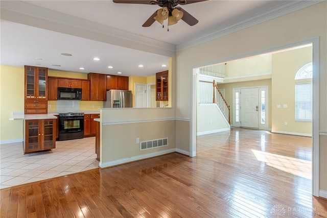 kitchen featuring ceiling fan, ornamental molding, black appliances, light countertops, and light wood-type flooring
