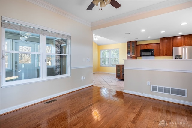 kitchen with visible vents, crown molding, black microwave, stainless steel fridge with ice dispenser, and a ceiling fan