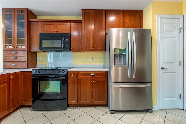 kitchen with black appliances, glass insert cabinets, light tile patterned floors, and light countertops