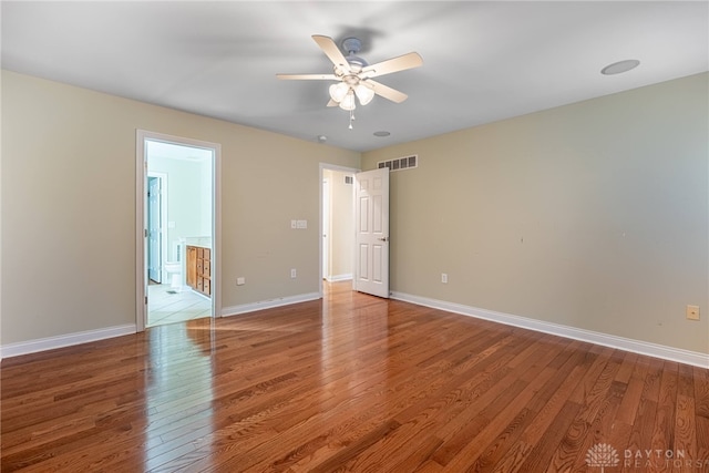unfurnished bedroom featuring visible vents, connected bathroom, ceiling fan, baseboards, and wood finished floors