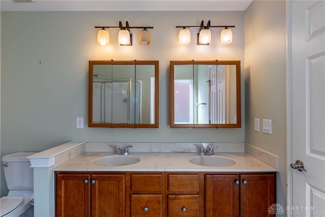 full bathroom with double vanity, toilet, visible vents, and a sink