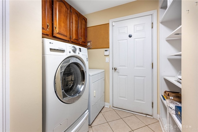 clothes washing area featuring cabinet space, light tile patterned floors, and washing machine and dryer
