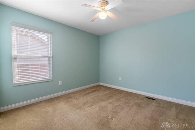 carpeted spare room with baseboards, visible vents, and ceiling fan