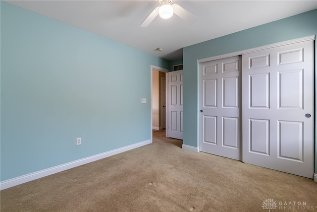 unfurnished bedroom featuring a closet, baseboards, light colored carpet, and ceiling fan