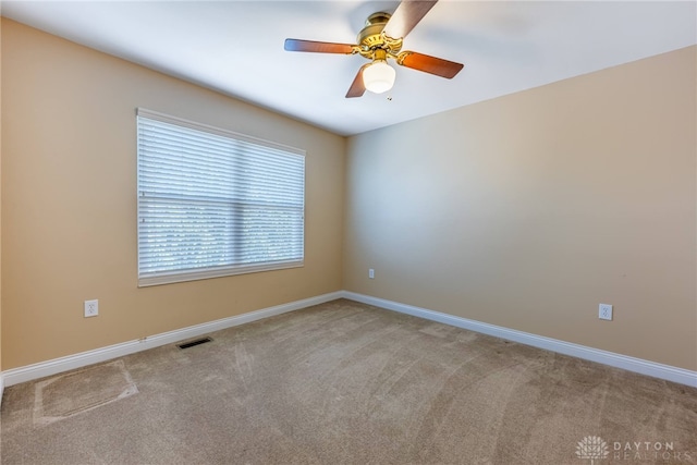 carpeted spare room featuring a ceiling fan, visible vents, and baseboards