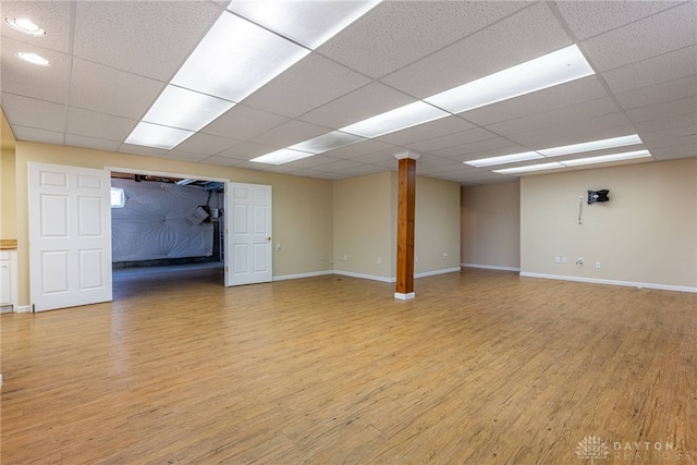 interior space featuring a drop ceiling, light wood-type flooring, and baseboards