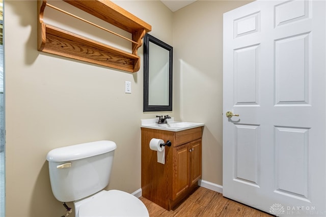 bathroom with baseboards, toilet, wood finished floors, and vanity