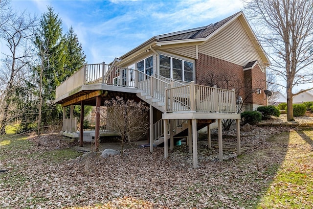 view of home's exterior featuring a wooden deck, brick siding, stairs, and a sunroom