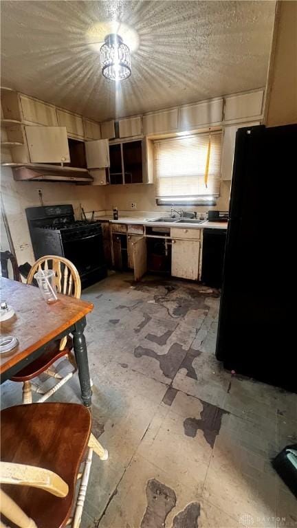 kitchen featuring light countertops, a sink, under cabinet range hood, and black appliances
