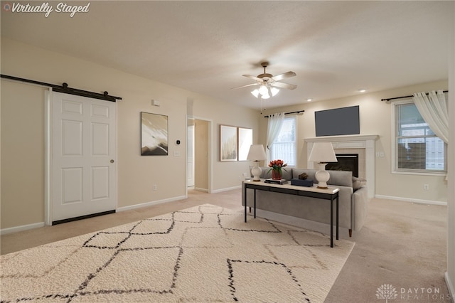 living area with a ceiling fan, light colored carpet, and baseboards