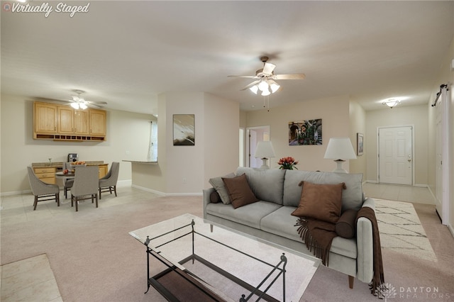 living room featuring light carpet, baseboards, and a ceiling fan