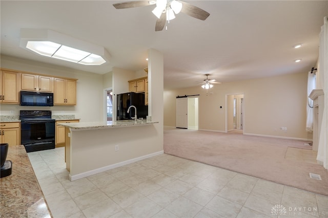 kitchen with light brown cabinets, ceiling fan, black appliances, light carpet, and a barn door