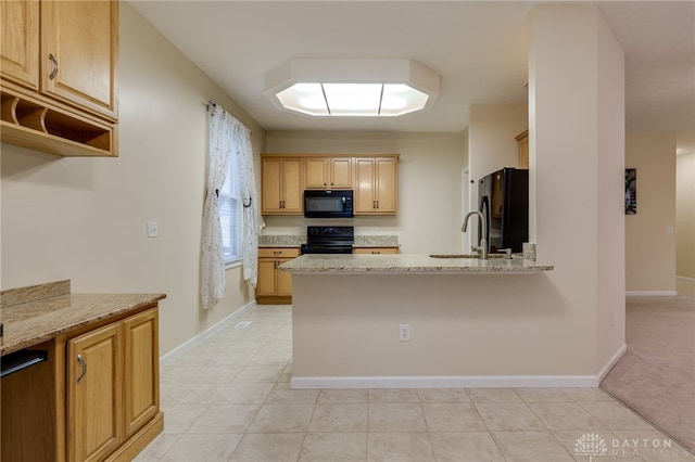 kitchen featuring light stone countertops, baseboards, a peninsula, a sink, and black appliances