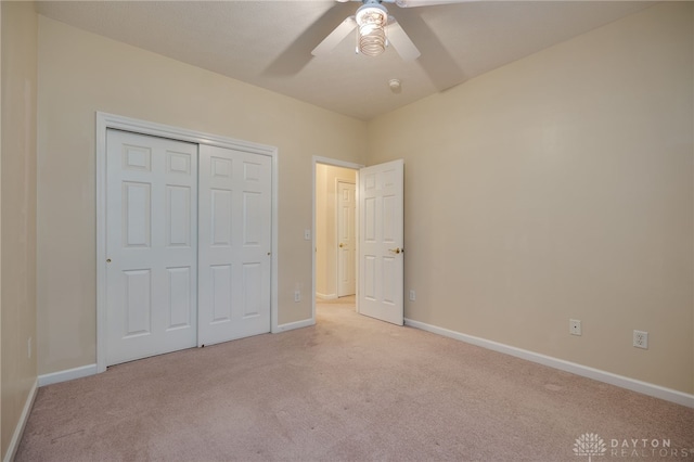 unfurnished bedroom featuring a closet, baseboards, light colored carpet, and a ceiling fan