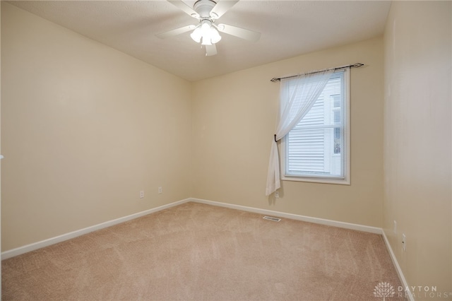 spare room with visible vents, light colored carpet, baseboards, and ceiling fan