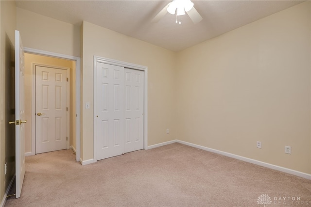 unfurnished bedroom with a ceiling fan, light colored carpet, baseboards, and a closet