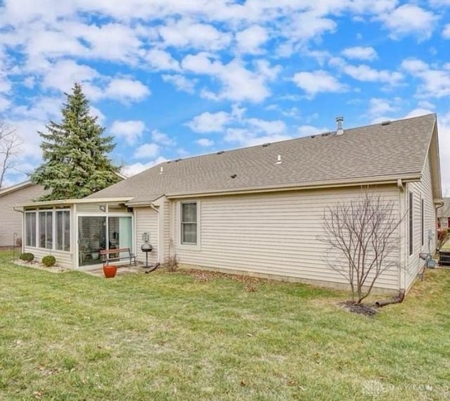 rear view of house with a yard, a sunroom, and a shingled roof