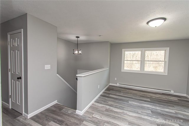 spare room with wood finished floors, baseboards, and a baseboard radiator