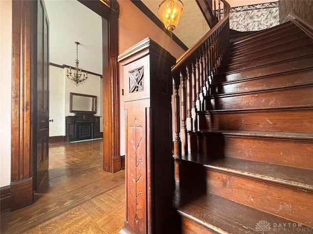 stairway with an inviting chandelier and wood finished floors