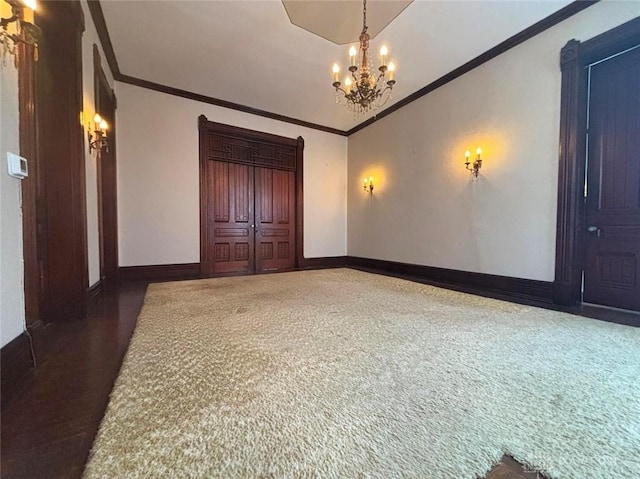 carpeted spare room with an inviting chandelier, crown molding, and baseboards