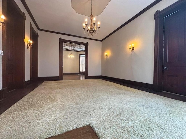 carpeted empty room with a chandelier, crown molding, and baseboards