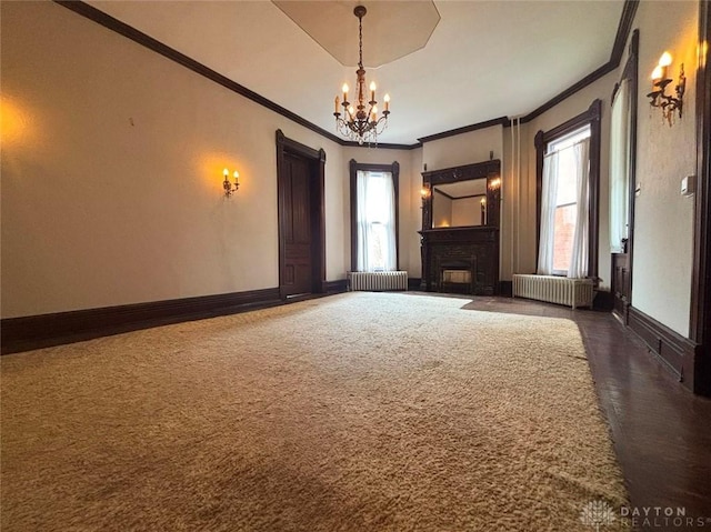 unfurnished living room featuring a chandelier, radiator, a fireplace, and baseboards