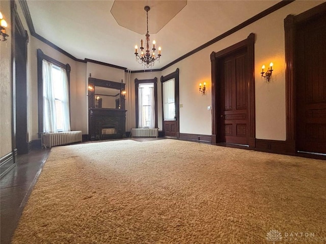 carpeted empty room featuring a wealth of natural light, radiator, and a chandelier