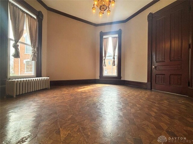 spare room with crown molding, radiator heating unit, baseboards, and a wealth of natural light