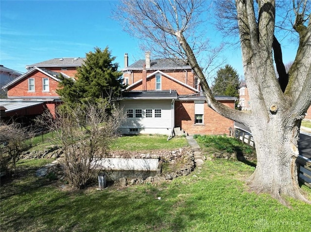 rear view of property featuring a lawn and brick siding