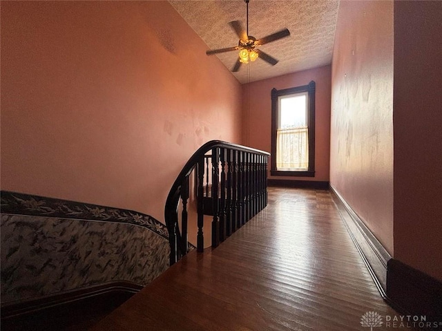 bedroom featuring a ceiling fan, wood finished floors, baseboards, vaulted ceiling, and a textured ceiling