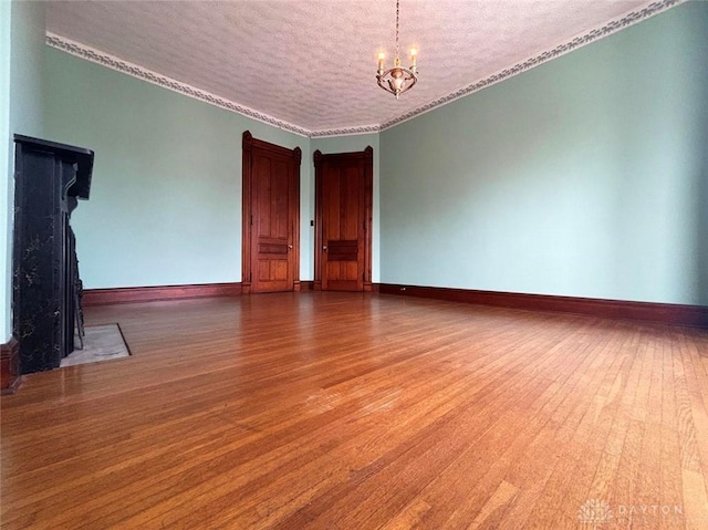 unfurnished room featuring baseboards, an inviting chandelier, and wood finished floors