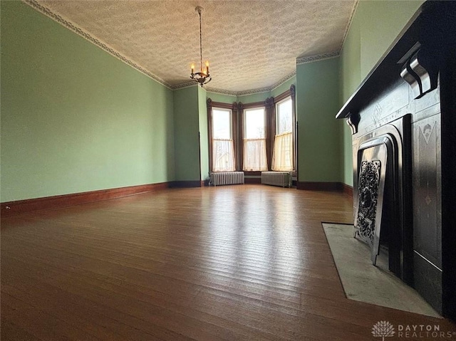 unfurnished living room with radiator, wood finished floors, a fireplace with flush hearth, and ornamental molding