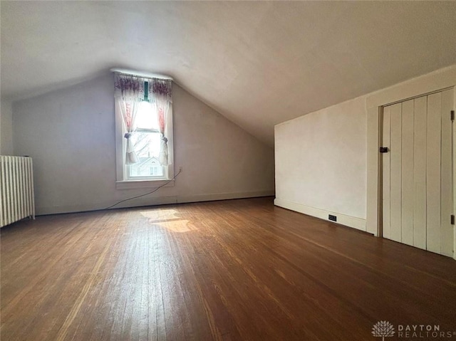 bonus room featuring wood finished floors, radiator heating unit, and vaulted ceiling