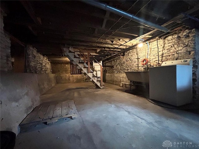 unfinished basement with stairway and washer / dryer