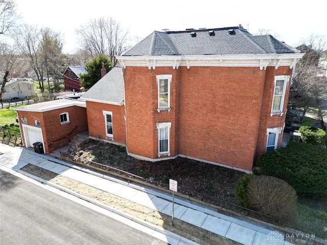 view of side of property with brick siding and roof with shingles