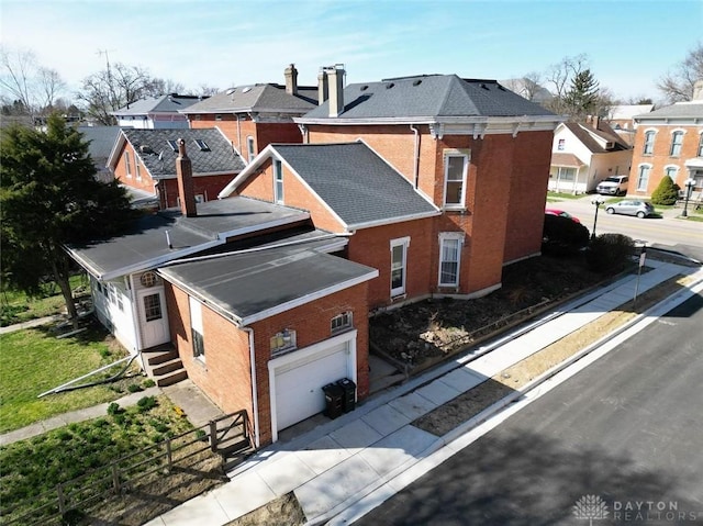 view of side of home with a residential view, brick siding, an attached garage, and fence