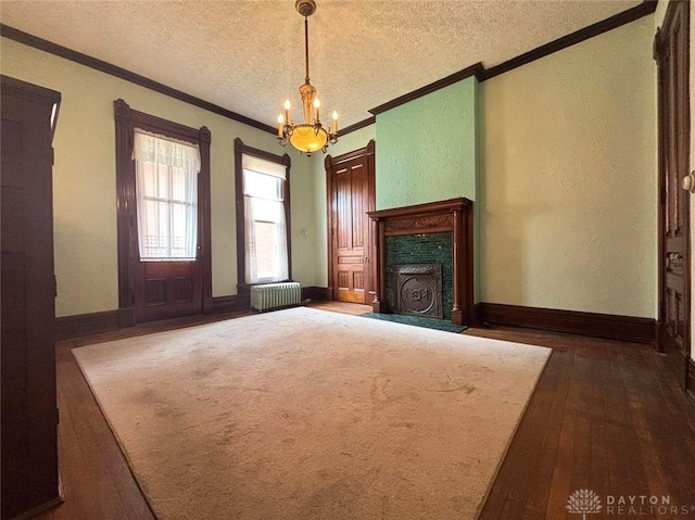 unfurnished living room with a textured ceiling, dark wood-style floors, radiator heating unit, an inviting chandelier, and crown molding