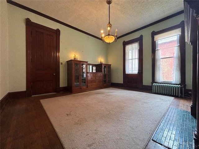 interior space featuring radiator, wood finished floors, a textured ceiling, crown molding, and a notable chandelier