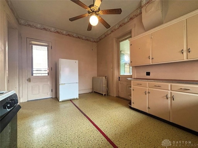 kitchen featuring black gas stove, radiator heating unit, ornamental molding, freestanding refrigerator, and a ceiling fan