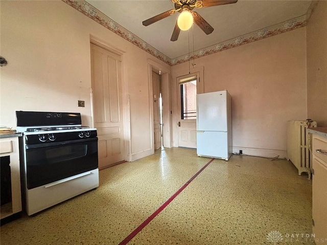 kitchen with freestanding refrigerator, radiator, gas range, baseboards, and ceiling fan
