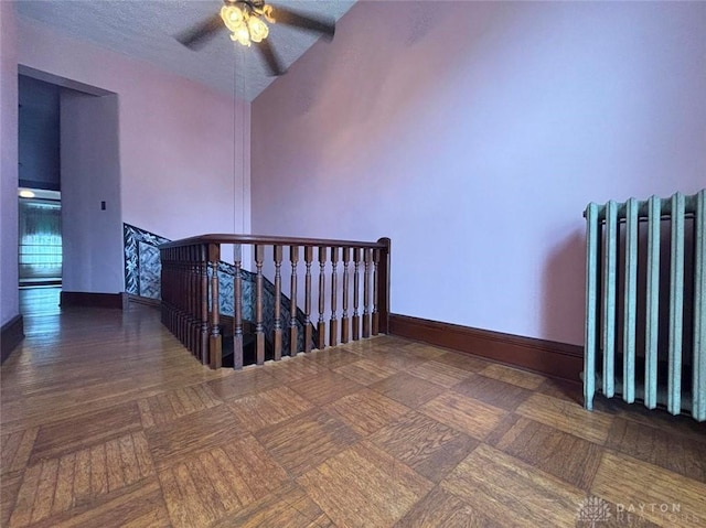 staircase featuring baseboards, radiator, a ceiling fan, and a textured ceiling