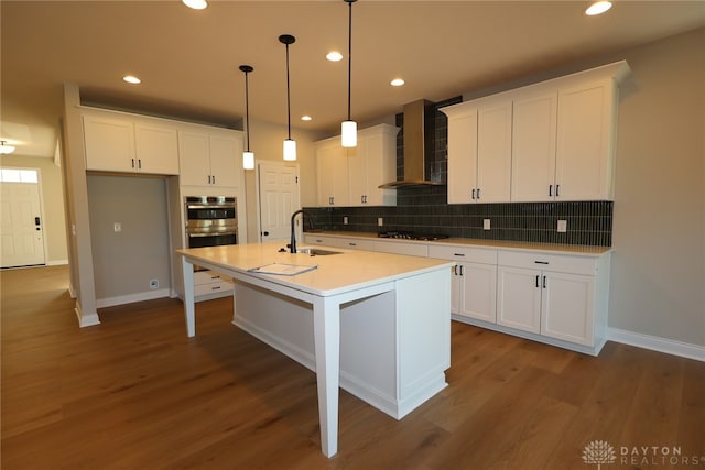 2855 Sky Crossing Dr Unit 50, Beavercreek, OH 45434 - kitchen featuring wall chimney range hood, stainless steel double oven, gas cooktop, tasteful backsplash, and white cabinets