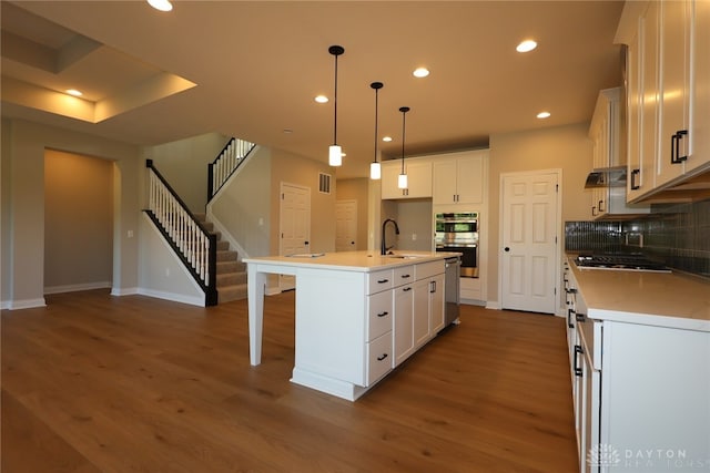 2855 Sky Crossing Dr Unit 50, Beavercreek, OH 45434 - kitchen with dark wood-style flooring, appliances with stainless steel finishes, white cabinetry, tasteful backsplash, and a breakfast bar area