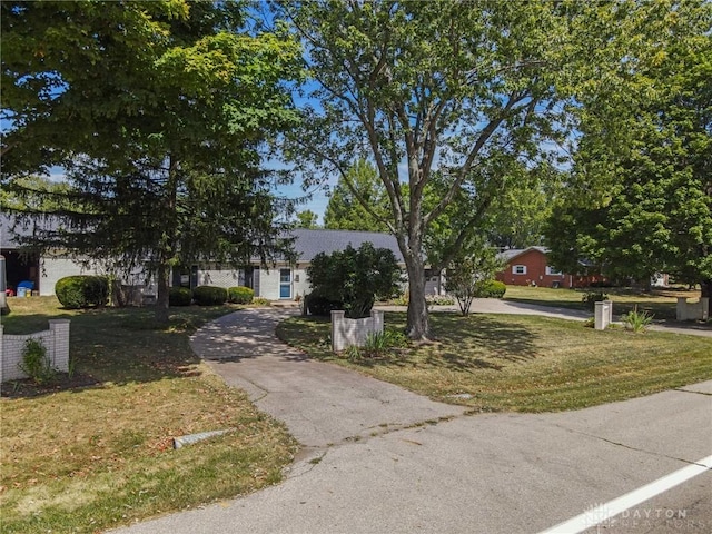 view of property hidden behind natural elements featuring a front yard and aphalt driveway