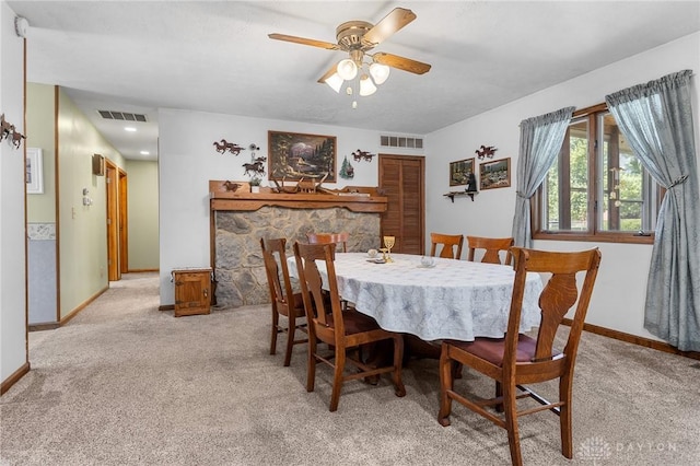 dining space featuring baseboards, ceiling fan, light carpet, and visible vents