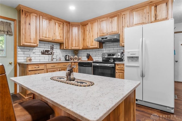 kitchen with appliances with stainless steel finishes, decorative backsplash, under cabinet range hood, and dark wood-style floors