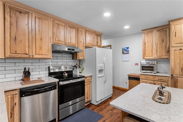 kitchen featuring appliances with stainless steel finishes, backsplash, a toaster, under cabinet range hood, and dark wood-style floors